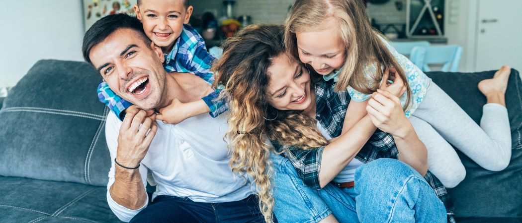 young family of four laughing on a couch